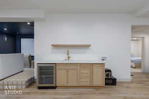Indoor wet bar featuring light brown cabinets, open shelves, beverage cooler, light wood-style floors, and recessed lighting