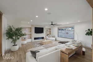 Living area with light wood-style flooring, a fireplace, built in shelves, recessed lighting, and a ceiling fan