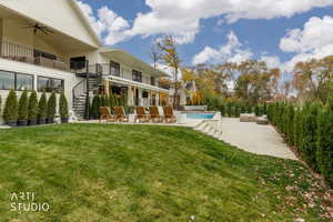 Swimming pool featuring a patio area, stairway, a balcony, and a yard