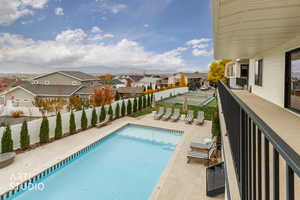View of pool featuring a residential view, a patio area, a fenced backyard, and a balcony