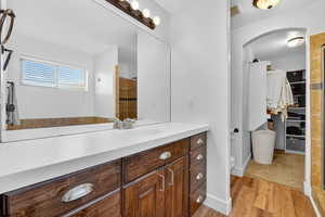 Full bathroom featuring vanity, light wood-style floors, a walk in closet, and tiled shower