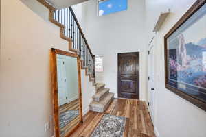 Entrance foyer with wood finished floors, stairs, and a high ceiling