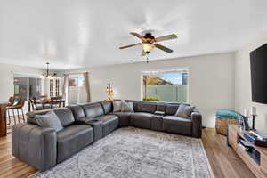 Living room featuring light wood-style floors, a chandelier, ceiling fan, and a textured ceiling