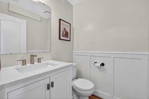 Bathroom featuring vanity, a wainscoted wall, and a decorative wall