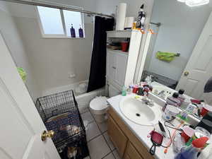 Full bath with vanity, light tile patterned flooring, and shower / bath combo with shower curtain