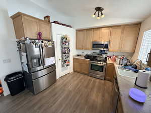 Kitchen featuring dark wood finished floors, stainless steel appliances, and brown cabinets