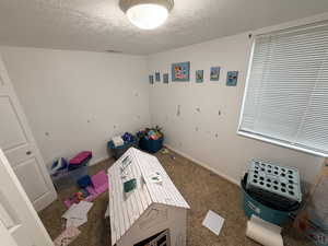 Carpeted bedroom featuring a textured ceiling and baseboards