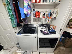 Laundry area featuring independent washer and dryer and light tile patterned floors
