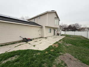 Rear view of house with a patio, a fenced backyard, and solar panels