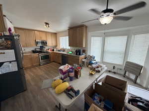 Kitchen with appliances with stainless steel finishes, dark wood-style flooring, light countertops, vaulted ceiling, and ceiling fan