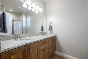 Bathroom with double vanity, curtained shower, and light tile patterned floors