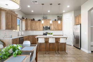 Kitchen featuring a kitchen bar, stainless steel appliances, pendant lighting, a kitchen island, and recessed lighting
