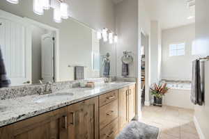 Full bathroom featuring double vanity, light tile patterned floors, and a garden tub