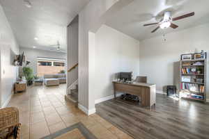 Home office with ceiling fan, tile patterned flooring, arched walkways, and a textured ceiling
