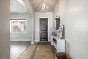 Foyer entrance with arched walkways, light wood-style floors, and a chandelier