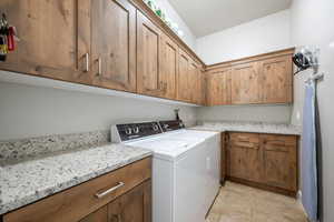 Laundry room featuring independent washer and dryer, cabinet space, and light tile patterned flooring