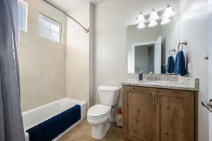 Full bathroom with vanity, shower / bath combo, and light tile patterned floors
