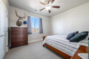 Bedroom featuring light colored carpet, ceiling fan, and a closet