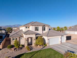 View of front facade featuring stone siding, an attached garage, driveway, and stucco siding