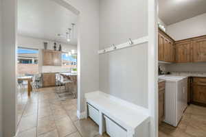 Laundry room featuring light tile patterned flooring, arched walkways, and cabinet space