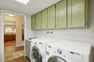Laundry room featuring dark wood-style flooring, separate washer and dryer, and cabinet space