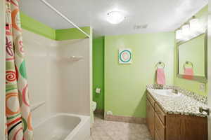 Full bathroom with vanity, a textured ceiling, shower / bath combo, and light tile patterned flooring