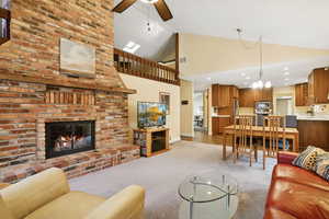 Living room with high vaulted ceiling, light carpet, a brick fireplace, and a chandelier