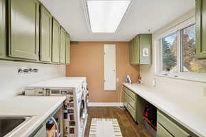 Washroom with dark wood-style floors, washing machine and clothes dryer, and cabinet space