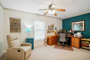 Home office with crown molding, light colored carpet, and a ceiling fan