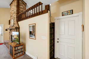 Carpeted foyer entrance featuring a fireplace and a high ceiling