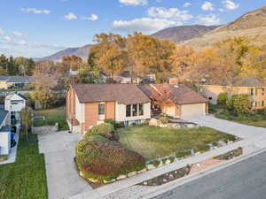 Ranch-style house with a mountain view, a front lawn, concrete driveway, and roof with shingles