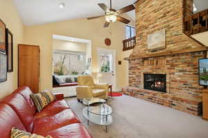 Carpeted living room featuring plenty of natural light, high vaulted ceiling, a fireplace, ceiling fan, and recessed lighting