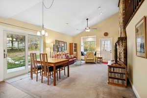 Dining room with high vaulted ceiling, a ceiling fan, carpet, and a chandelier