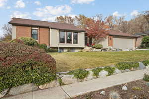 View of front of property featuring a front yard, a garage, brick siding, and a shingled roof