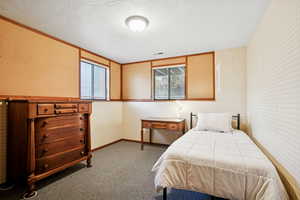 Carpeted bedroom with a textured ceiling, ornamental molding, and wallpapered walls