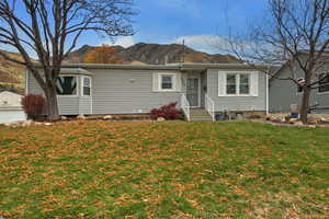 View of front of house with a mountain view, a front lawn, and entry steps