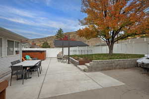 Fenced backyard featuring a hot tub, outdoor dining area, a patio, and a mountain view