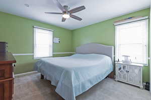 Carpeted bedroom with ceiling fan and baseboards