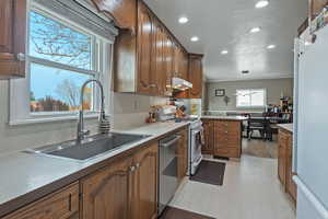 Kitchen featuring white appliances, light countertops, brown cabinetry, recessed lighting, and decorative light fixtures