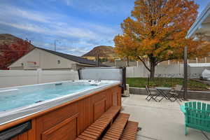 View of patio with a mountain view, outdoor dining space, and a hot tub