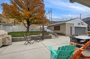 Fenced backyard featuring outdoor dining area, a patio, an outbuilding, and grilling area
