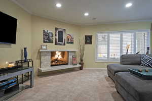 Living area featuring crown molding, a fireplace, carpet flooring, and recessed lighting