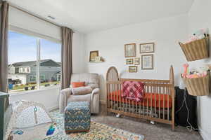 Carpeted bedroom featuring a nursery area and a residential view