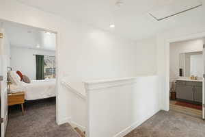 Corridor featuring dark carpet and an upstairs landing