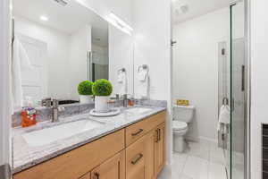 Full bath featuring double vanity, light tile patterned flooring, and a stall shower