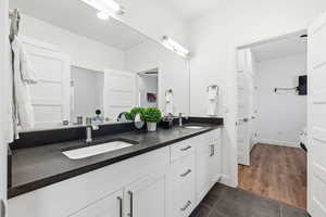 Bathroom featuring double vanity and dark tile patterned floors