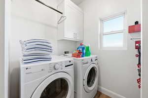 Laundry room with wood finished floors, washer and clothes dryer, and cabinet space