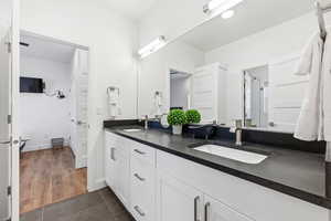 Full bathroom featuring double vanity and dark tile patterned floors