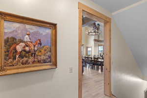 Hall with a chandelier, wood finished floors, and beam ceiling