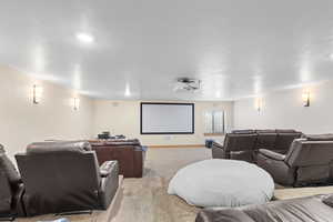 Carpeted home theater room with a textured ceiling and baseboards